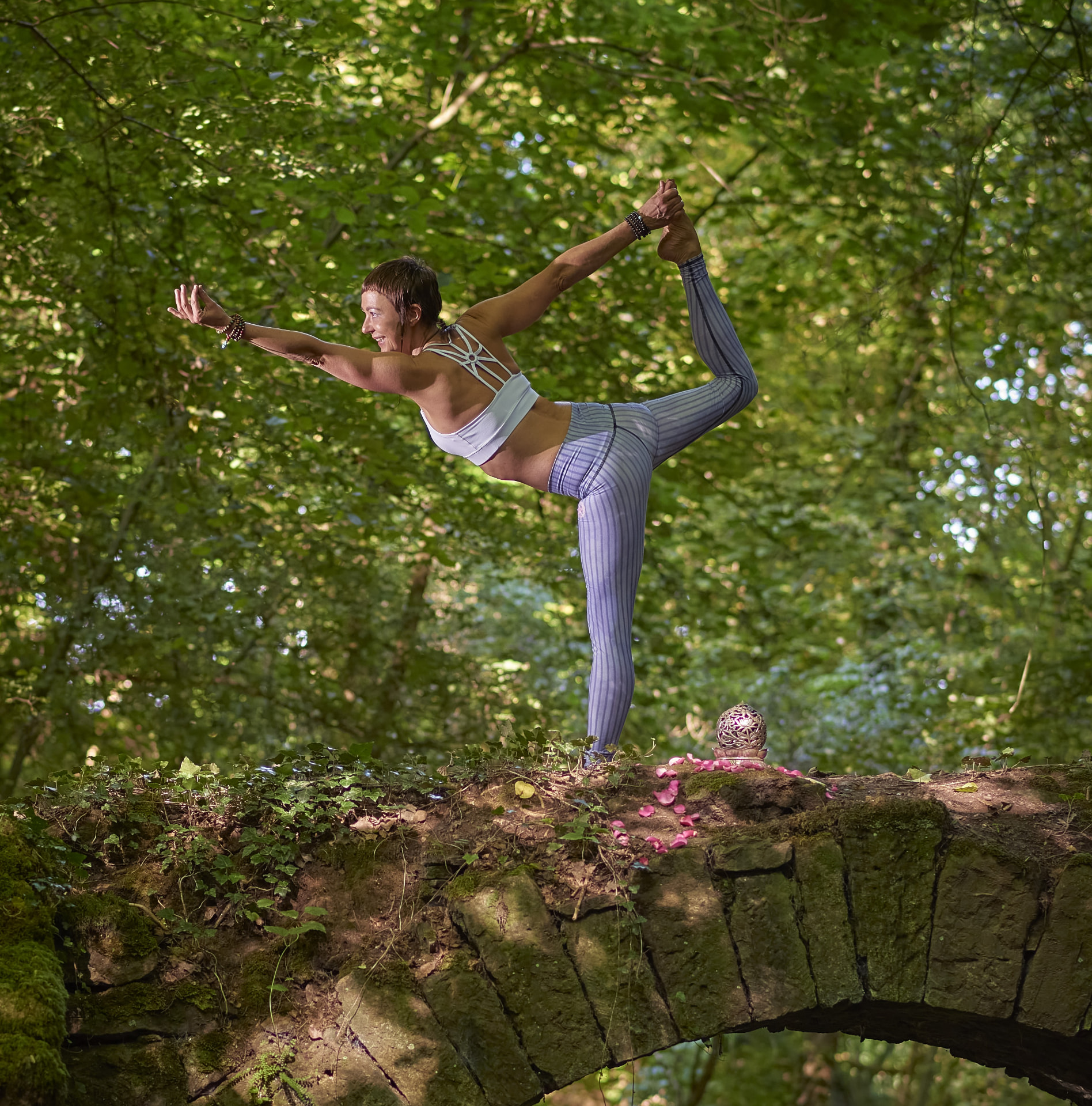 Yogahaltung Tänzerin auf einer Steinmauer im Wald