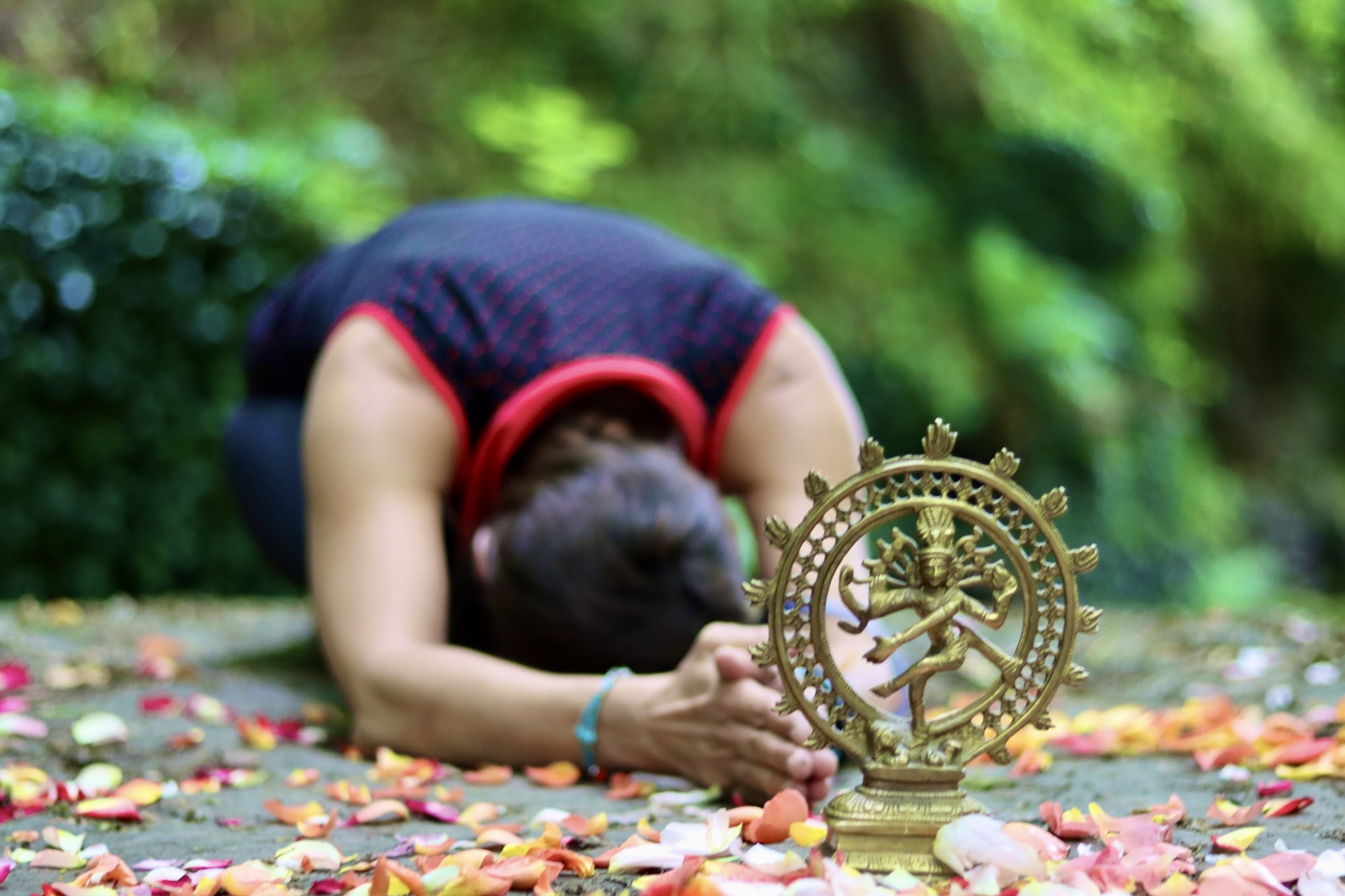 Yoga Mudra vor einer Shiva-Figur, umgeben von Blüten